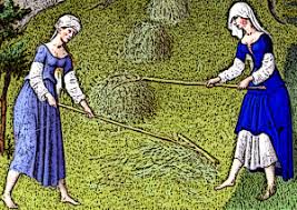 Two women raking straw in a field wearing long blue dresses over white tunics with white head coverings