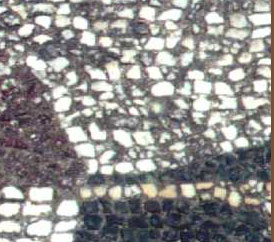 white and red mosaic stones cemented together into a floor