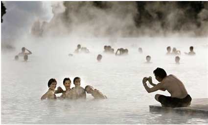 People bathing in hot springs with clouds of steam