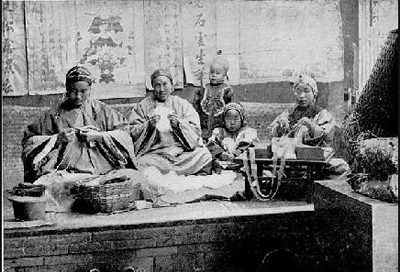 A k'ang bed in an old photo, with women sitting cross-legged on it