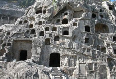 Rooms carved into the side of a big gray cliff, with stairs and walkways