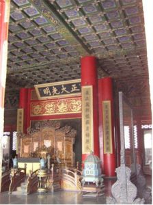 inside a hall with red pillars and a fancy throne