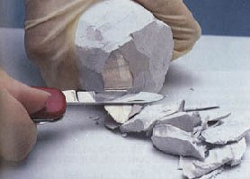 white male hands cutting a block of white stuff with a knife