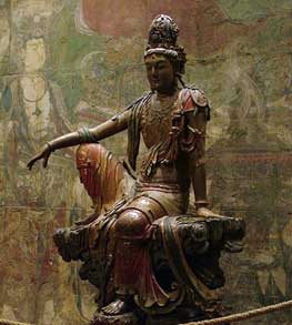 Kuan Yin statue of a woman sitting with one knee up and her arm resting on her knee