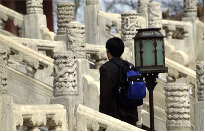 A Chinese man walking up a fancy carved white stone staircase