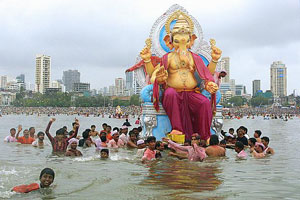 Worshipping Ganesh: a large gold elephant on a river with a crowd in the water