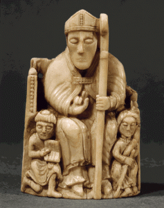 Ivory bishop sitting in a chair, with a pointed hat on, holding a shepherd's staff curved at the top in a spiral.