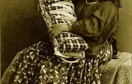 An Apache woman holding a baby in a cradleboard
