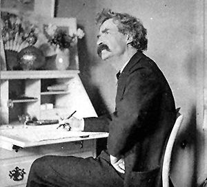 Mark Twain: a white man with shaggy hair sitting at a desk in a suit